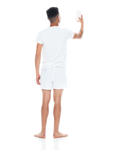 非裔美国青年男性穿着内衣站在白色背景前用手机拍照图片下载