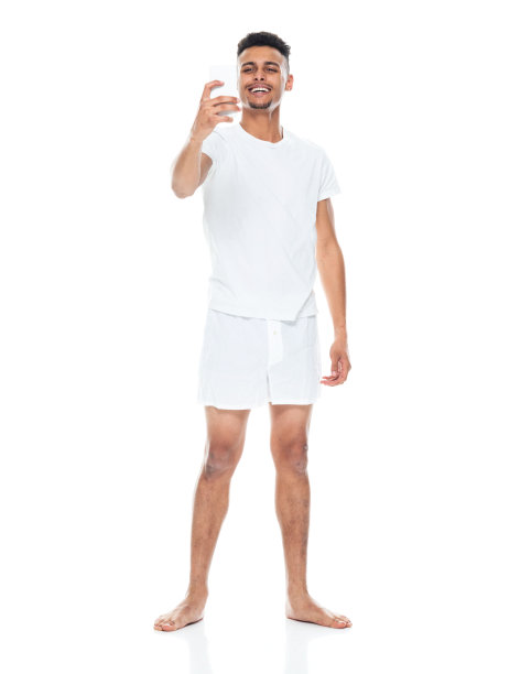 非裔美国青年男性穿着内衣站在白色背景前用手机拍照图片下载