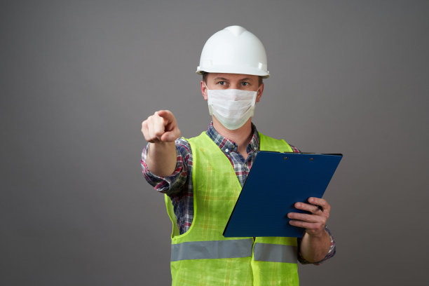 年轻的工程师戴着白色头盔和医用口罩图片下载