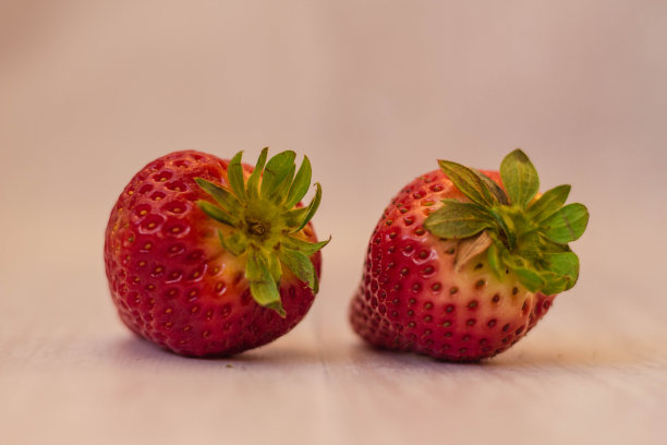 在浅棕色背景下分离出两个新鲜的红草莓图片下载