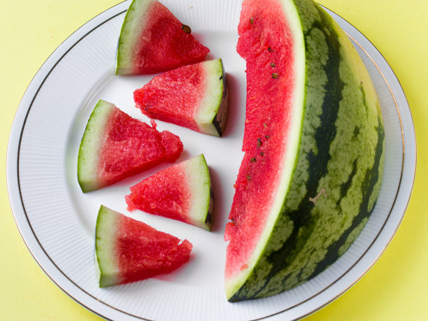 切片西瓜在白色盘子与勺子和叉子股票照片与白色背景。图片下载