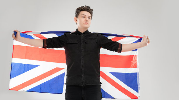 画室里一个灰色背景的白人男子的肖像。概念与复制空间。他们穿着黑衬衫，在镜头前摆姿势。英国国旗图片图片下载