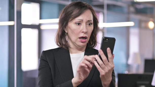 老女商人对智能手机上的损失的反应图片下载