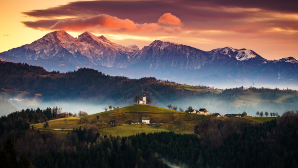 斯洛文尼亚Skofja Loka，日出时的圣托马斯教堂，背景是Kamnisko Savinjske Alpe图片下载