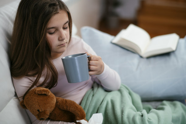 漂亮的小女孩在家喝茶库存照片。图片下载