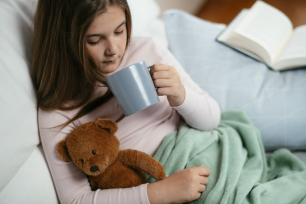 漂亮的小女孩在家喝茶库存照片。图片下载