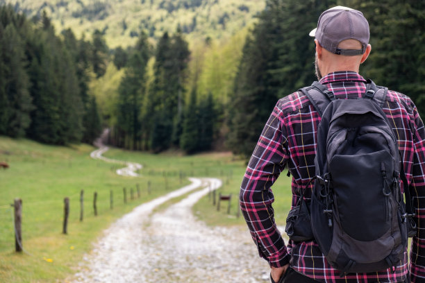 男人徒步穿越美丽的绿色山谷素材图片