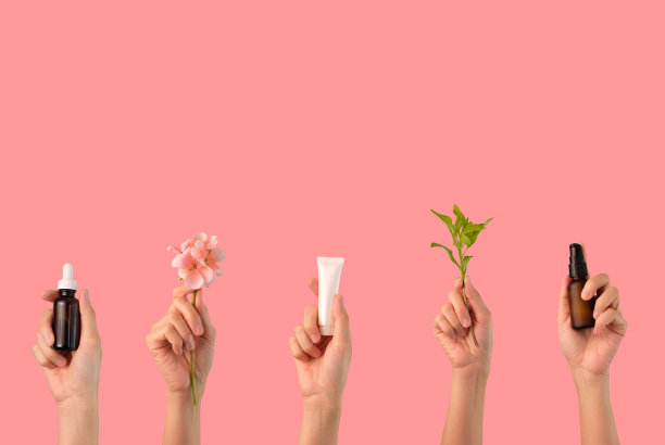 化妆品护肤常规瓶，滴管，泵瓶与有机叶片和花卉成分在粉红色的背景。图片下载