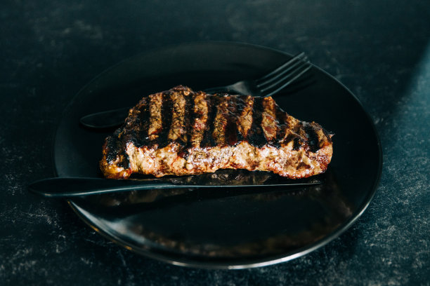 用刀叉在户外燃气烤架上烤过的单块牛腰肉图片下载