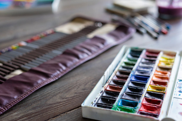 彩色铅笔、画笔和水彩颜料放在木桌上。艺术画家配件。前光，选择性聚焦图片下载