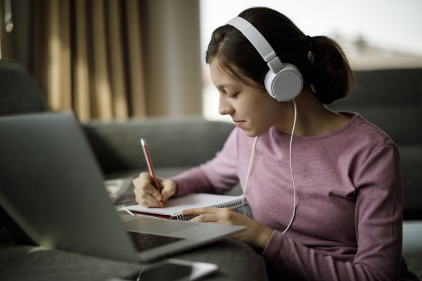 十几岁的女孩戴着耳机在家学习图片下载