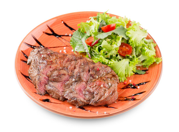 烤切片牛排配沙拉，西红柿和酱汁在一个橙色的盘子上孤立的白色图片下载