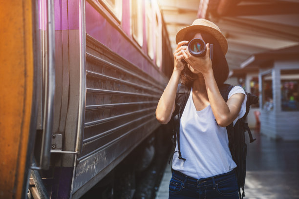 一名女游客在铁路背景上用相机拍照。年轻的亚洲女性旅行者背包在铁路，旅游概念图片下载