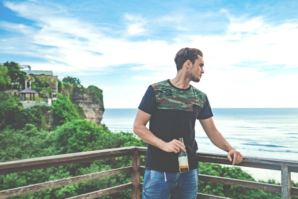 在假期里喝啤酒，看远处的海景。图片下载