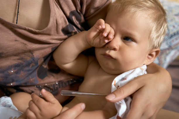 特写婴儿与温度计在母亲的怀抱图片下载