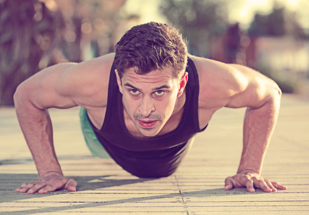 在户外做俯卧撑的运动型男人图片下载