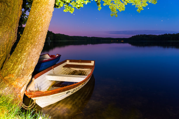 美丽的夜湖景观。小船在湖岸上。图片下载