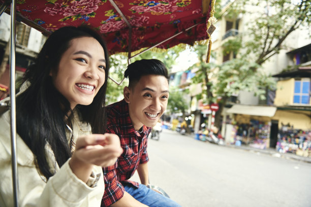 一对夫妇坐着越南人力车，指着什么东西图片下载