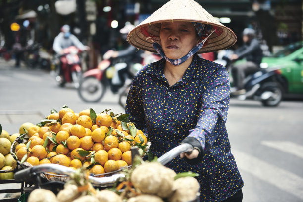 在城市街道上骑自行车卖水果的越南妇女图片下载