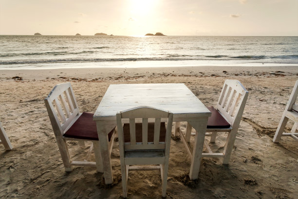 空荡荡的沙滩餐厅，只有木桌，没有顾客。热带酒吧和岛屿景色与平静的海水图片下载