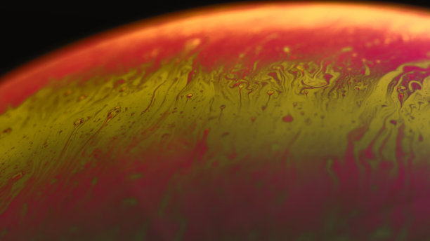 肥皂泡抽象微距照片美丽迷幻抽象红黄色阴影黑色背景。球体表面图片下载