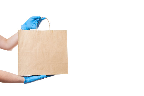 在新冠肺炎大流行检疫期间，用环保工艺标签包装安全递送食品的快递员手戴无菌手套，白色背景上有拷贝空间。图片下载