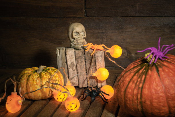 木桌背景下的万圣节南瓜灯串、蜘蛛与骷髅图片下载