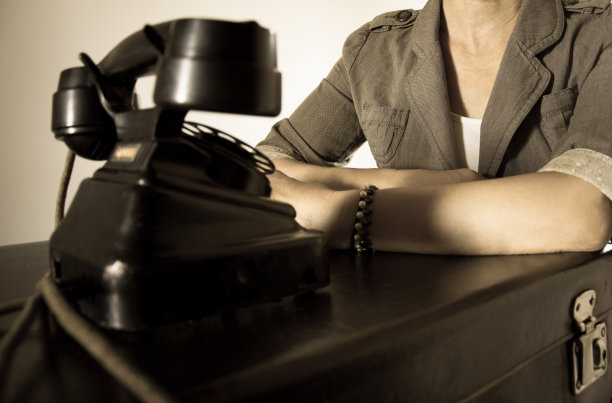 拿着老式行李箱的女人正在等电话。图片下载