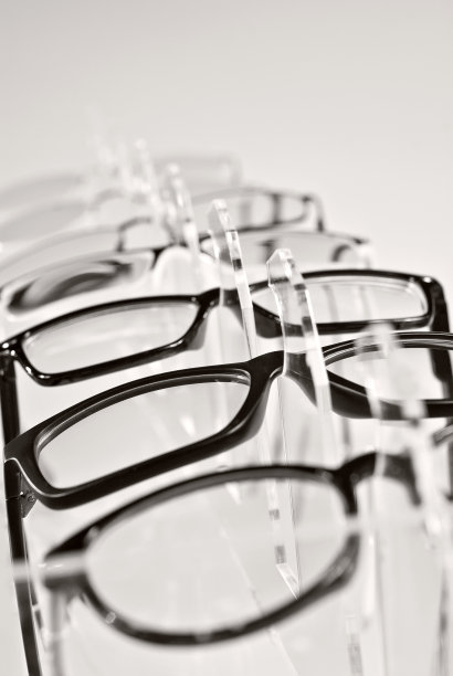 白色背景上的许多眼镜。透明的橱窗上堆放着一排玻璃。玻璃支架放在灰色的桌子上。光学产品销售及展览。图片下载