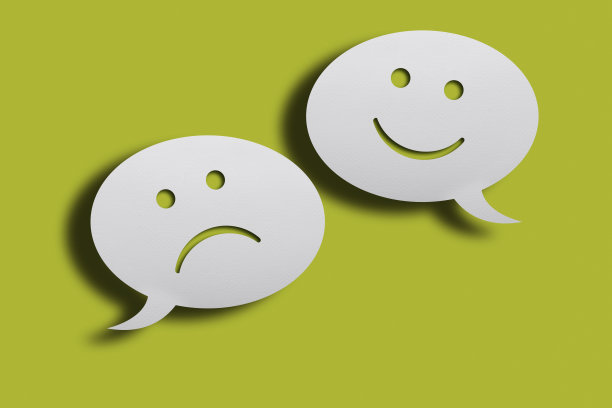 白色聊天气泡与快乐和悲伤的脸表情在绿色的背景。图片下载