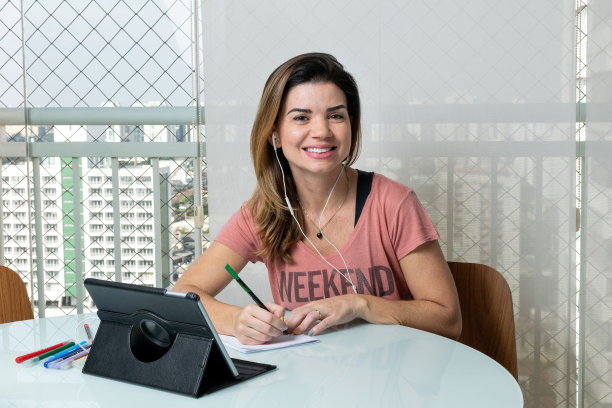 成熟的女人在网上做心理咨询，对着镜头微笑(家庭办公室)。图片下载