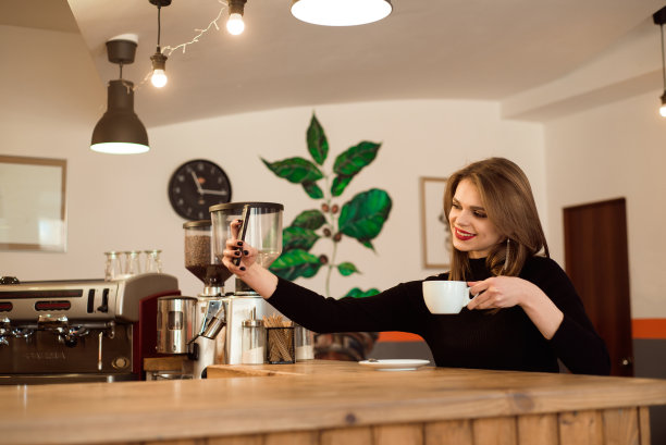 微笑的女孩在咖啡店拿着电话。图片下载