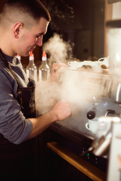 微笑的男咖啡师使用专业的咖啡机享受在咖啡馆的工作，提高技巧的卡布奇诺图片下载