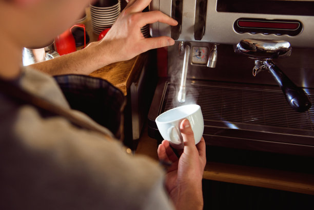 详细的咖啡师准备新鲜的浓缩咖啡在工业酿造机械。图片下载