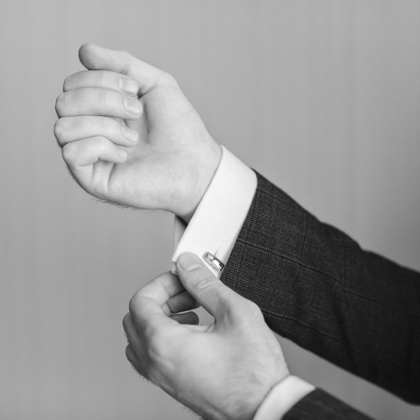 商人戴袖扣的特写。优雅的年轻时尚商人穿着西装。图片下载