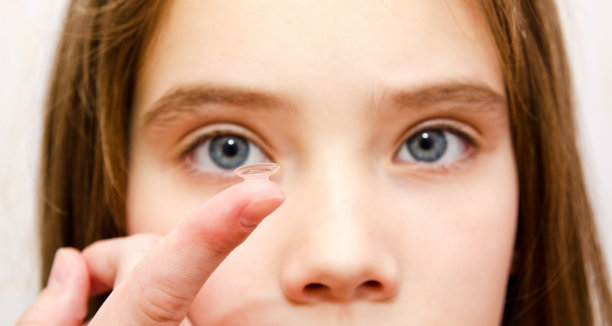 小女孩把隐形眼镜放进她的眼睛特写镜头图片下载