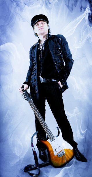 酷酷的摇滚吉他手在一个发光的蓝色背景下站在电吉他与修饰/改变的吉他床头。在工作室摆姿势的音乐家。图片下载