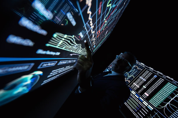 在黑暗的房间里，站在大屏幕旁边的商人图片下载