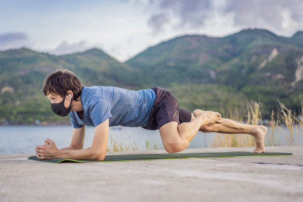 在冠状病毒隔离期间，年轻男子戴着医用口罩在公园里进行一些锻炼。运动、生活中积极隔离外科消毒口罩防护。在Corona Outbreak的田径跑道上进行户外跑步图片下载