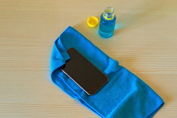黑色手机正在干燥后的消毒液上的蓝色餐巾。用于手部卫生的瓶中消毒液保护冠状病毒的背景。世界流行的冠状病毒(COVID-19)图片下载