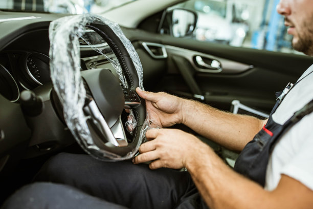 一个不知名的修理工正在拆方向盘上的塑料。图片下载