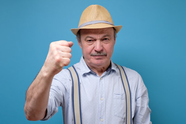 年长者戴着夏天的帽子生气而发狂，举起拳头沮丧而愤怒。图片下载