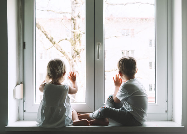 被隔离的小孩子正在家里看窗外。孩子们在家休闲的照片。图片下载