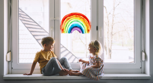 小孩子在窗户上画彩虹的背景上。孩子们在家休闲的照片。图片下载