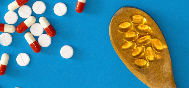 节食的概念。孤立的蓝色背景与鱼油胶囊上的木勺在一个图片的中心。平躺，俯视图。图片下载