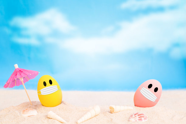 五颜六色的鸡蛋戴着织物面具，在白色的沙滩上越过阴天的背景图片下载