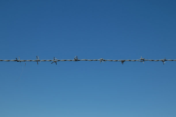 蓝色的天空映衬着紧张的铁丝网图片下载