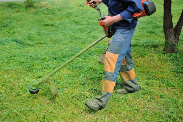 一个穿着普通工人制服的人在草坪上工作。图片下载