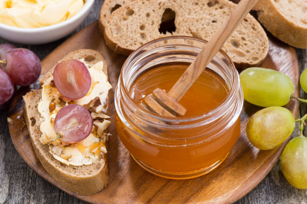 蜂蜜调味，面包黄油和葡萄在木板上，俯视图，水平图片下载