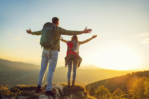 夫妇举起手臂，手牵着手，看着夕阳图片下载